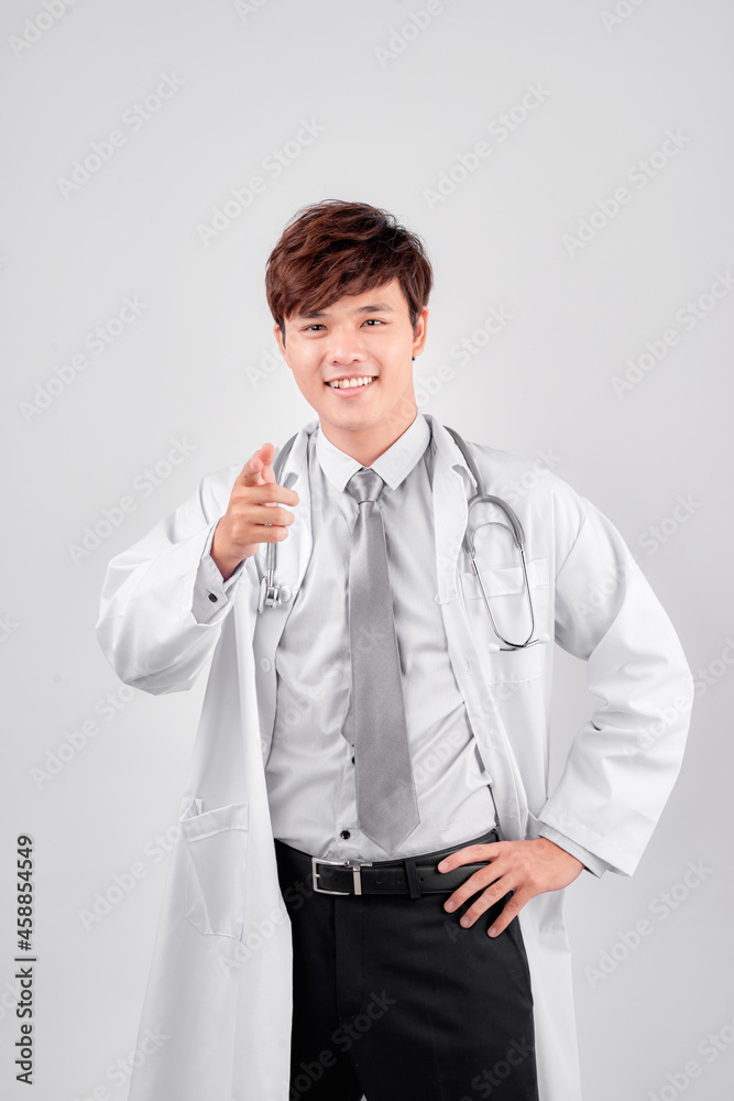Smiling positive young doctor in labcoat pointing away, isolated on white Smiling positive young doctor in labcoat pointing away, isolated on white