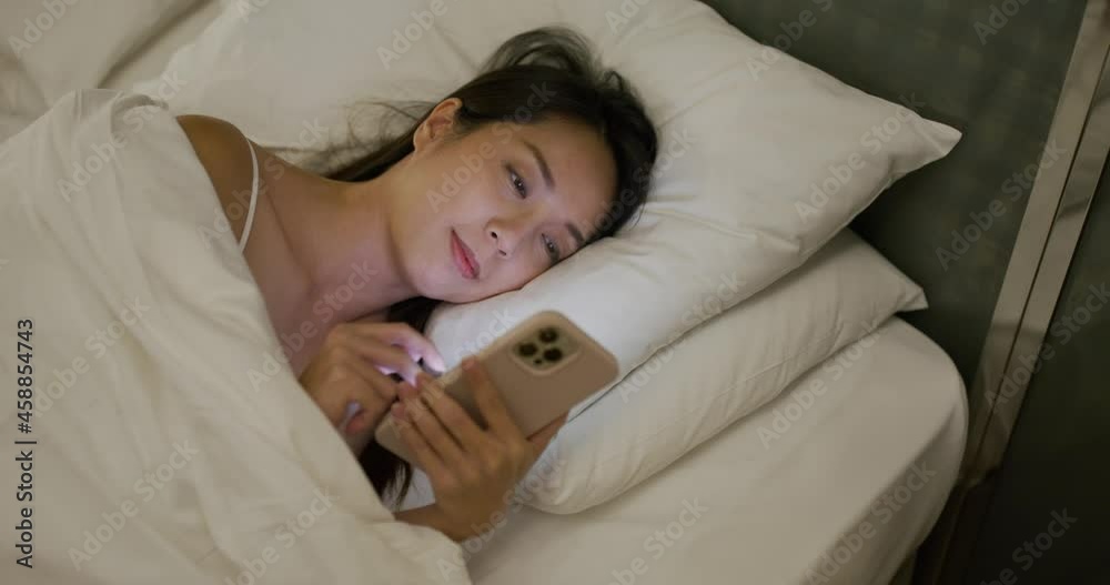 Woman lying on bed and use cellphone at night Woman lying on bed and use cellphone at night