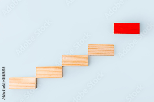 Fototapeta Naklejka Na Ścianę i Meble -  Leadership and influencer concept. Wooden blocks stacking as step stair and following one red on blue background. Individuality and uniqueness. Social distance. Dominant leader.