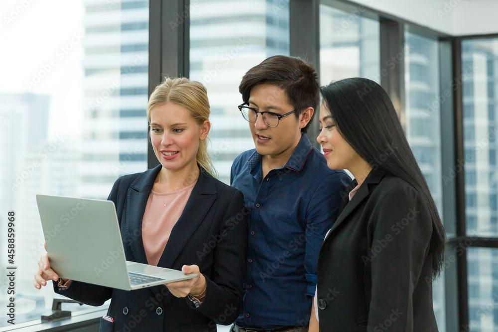 Diverse business people wear formal suit standing and using computer laptop at the office. Group of colleagues standing and working with computer laptop at work