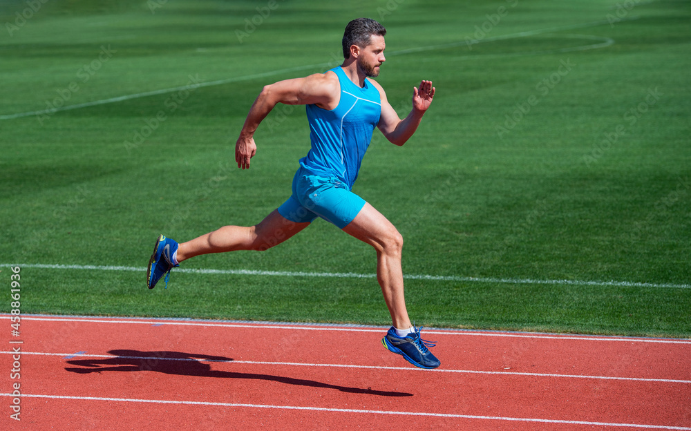 Obraz premium athletic muscular man running in sportswear on stadium track, stamina