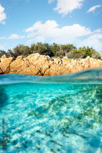 Split shot  over under photo. Half underwater with turquoise water and a rocky coast on the water surface. Prince Beach  Spiaggia del Principe  Sardinia  Italy.