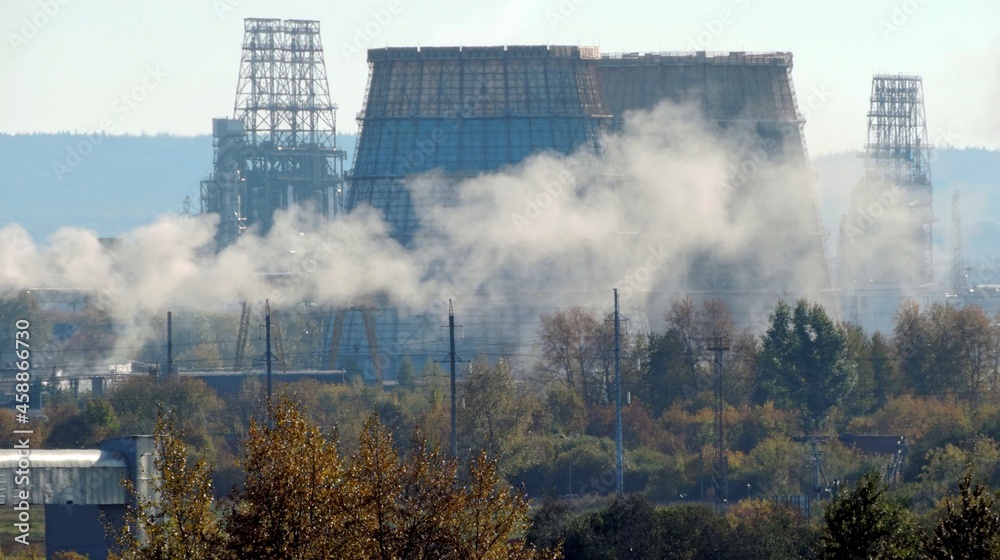 Huge cooling towers of a thermal power plant. An oil plant is on the horizon. Smoke from production pipes. Huge cooling towers of a thermal power plant. An oil plant is on the horizon. Smoke from production pipes.