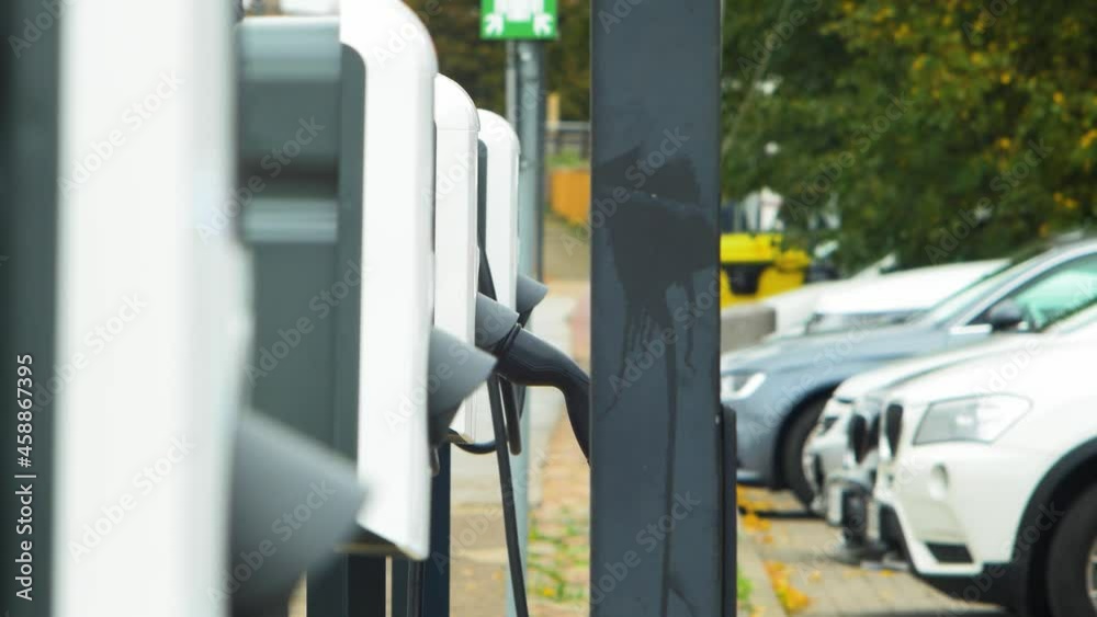 Electric cars charging station system on a city street, a cable connected to a car, future of the automobile, clean sustainable energy, overcast day, defocused medium shot