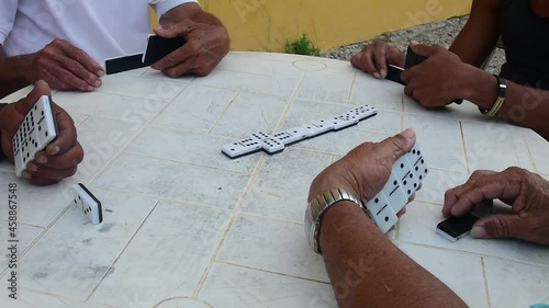 Multiethnic group of men PLAYING DOMINO on white plastic table in caribbeaan island. Close up photo