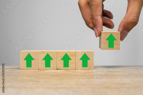 hand holding wooden cube with green arrow.gain up concept