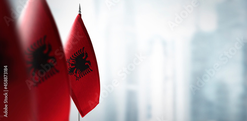 Small flags of Albania on a blurry background of the city