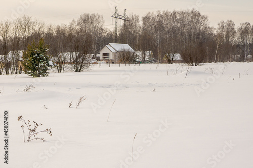 outskirts of the village in winterThe outskirts of a rural settlement near a forest in winter, traces of wild animals covered by snow are visible in the snow