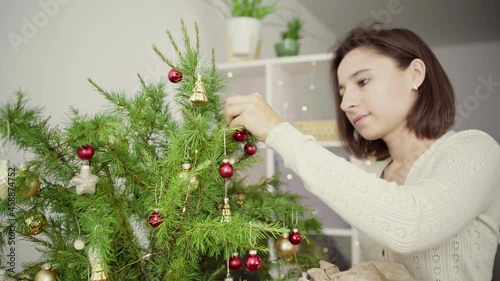 Young woman decorates a Christmas tree with luminous garlands.Merry Christmas and Happy Holidays. The morning before Xmas. 