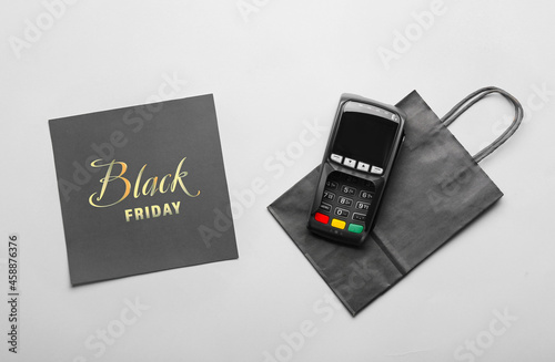 Shopping bag, payment terminal and card with text BLACK FRIDAY on light background