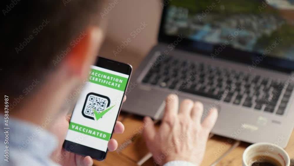 Man drinking coffee in a restaurant showing digital vaccine passport. COVID Pass for entry to restaurants, cinemas, shopping malls, hospitals Man drinking coffee in a restaurant showing digital vaccine passport. COVID Pass for entry to restaurants, cinemas, shopping malls, hospitals