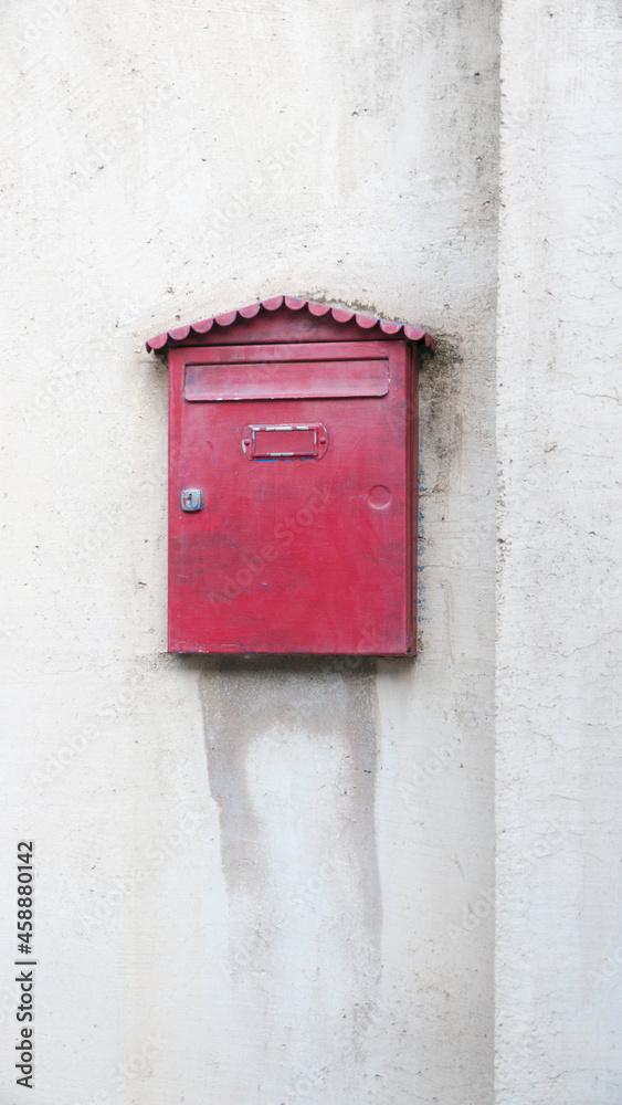 Buzon de correo rojo metálico en pared blanca vieja