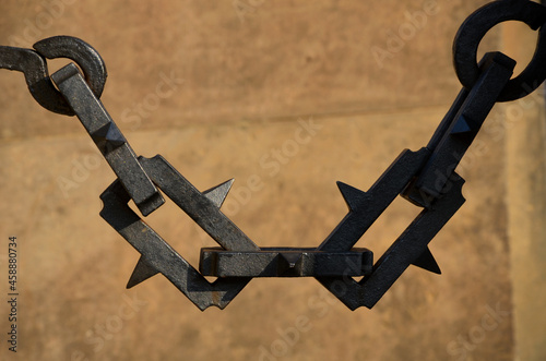 solid steel chain with rectangular mesh. there is a steel spike on each part. it resembles barbed wire. monument to fallen heroes in world war.