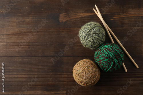 Yarn balls and knitting needles on wooden background