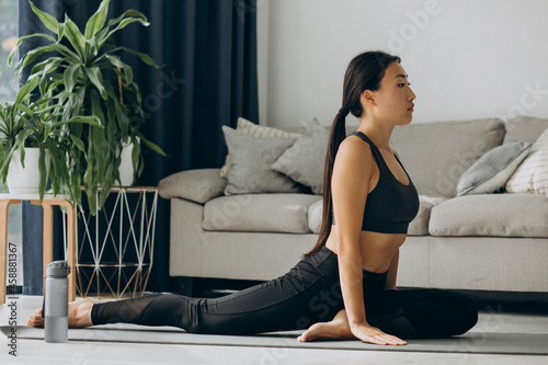 Woman stretching on yoga mat at home