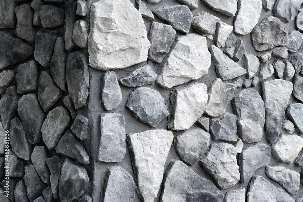 Black and white background of a stone wall.The corner walls are made by hand from concrete and stone, as the decor of a modern building.Background of an ancient stone wall. Black and white background of a stone wall.The corner walls are made by hand from concrete and stone, as the decor of a modern building.Background of an ancient stone wall.