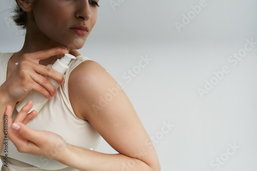 woman in white t-shirt applies cream to skin close-up