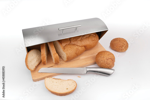 Bread bin. Kitchen ware. Fresh baked sesame buns in wooden  and steel box with bread knife photo