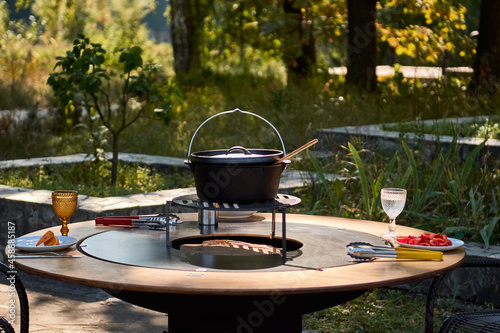 Kettle Grill Pit with Cast Iron Grid with flames . Round table-cooking surface. Hot BBQ on Backyard