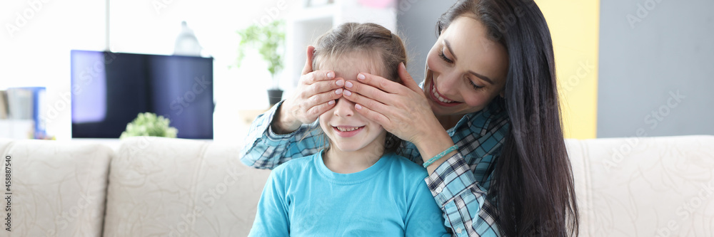 Young mother closes her daughter eyes and gives her gift Young mother closes her daughter eyes and gives her gift
