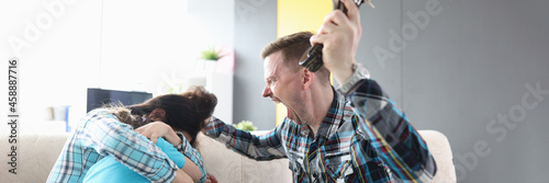 Angry man yells at his wife and child holding belt in his hand