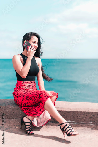 Young woman is sitting on the street during talking by phone and looking forward. Connecting people concept
