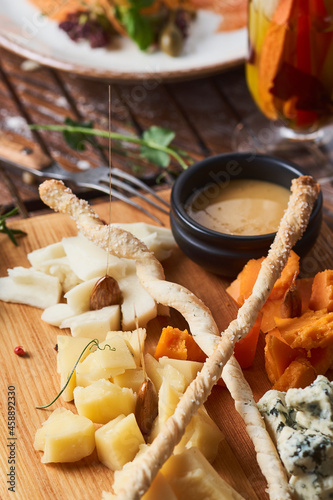 antipasti, different types of cheese on a wooden board with honey