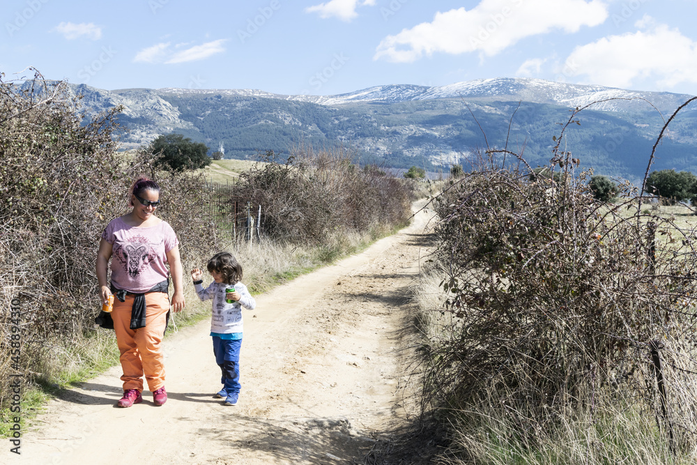 A single-parent family strolls through nature, avoiding crowds of people