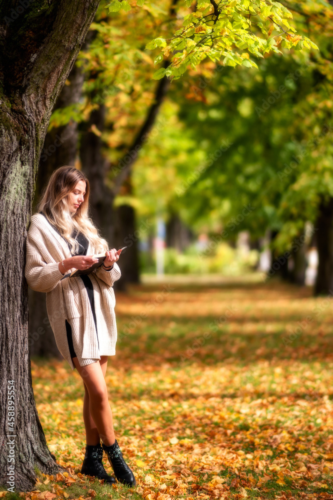 Stylish girl reading book in colorful autumn park Stylish girl reading book in colorful autumn park