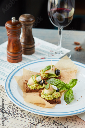 bruschetta on a wooden table in a white plate and a glass of red wine
