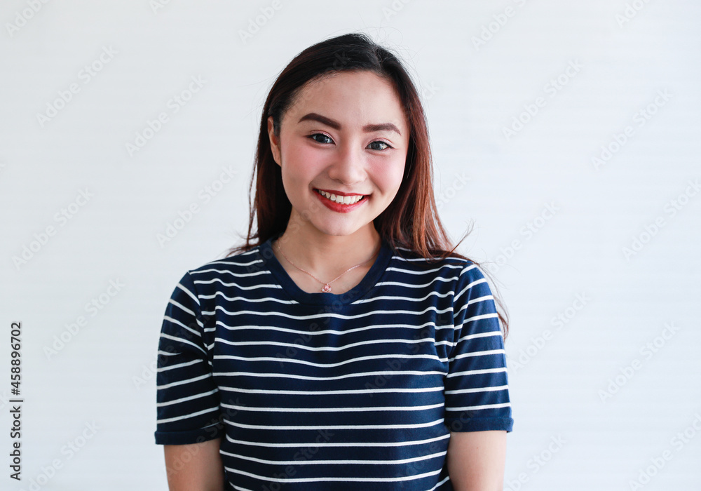 Studio portrait close up shot of Asian young happy beautiful pretty charming cheerful joyful long hair female model wears stripe casual clothing smiling show teeth look at camera on white background Studio portrait close up shot of Asian young happy beautiful pretty charming cheerful joyful long hair female model wears stripe casual clothing smiling show teeth look at camera on white background
