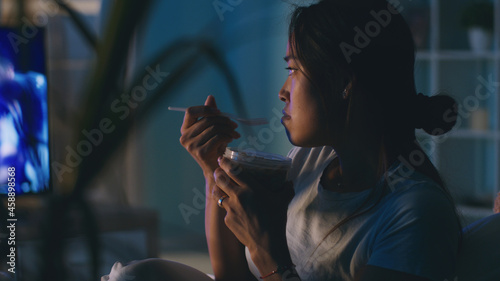 Asian woman eating and watching TV