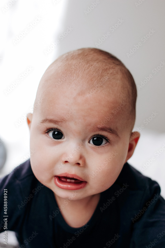 Sweet chubby cheeky baby boy lying on his tummy on the bed. Funny face expression. Sweet chubby cheeky baby boy lying on his tummy on the bed. Funny face expression.