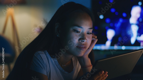 Asian female watching video on tablet in evening