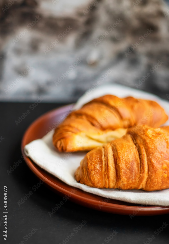Fresh croissants on a clay plate on a dark background Fresh croissants on a clay plate on a dark background