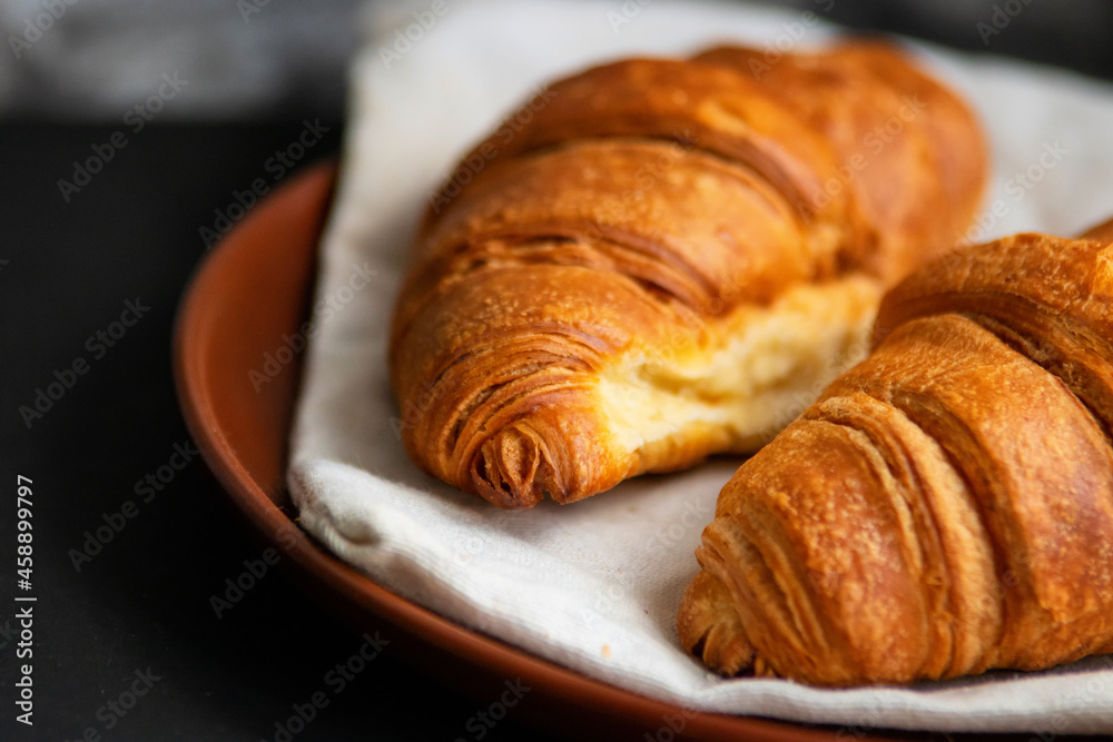 Fresh croissants on a clay plate on a dark background Fresh croissants on a clay plate on a dark background