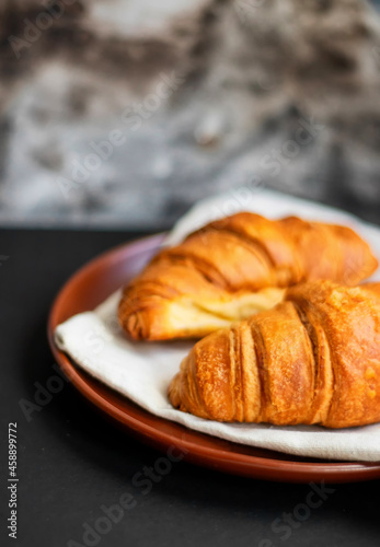 Fresh croissants on a clay plate on a dark background