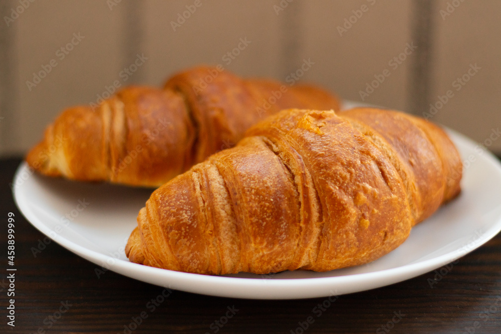 Fresh croissants on a white plate on a dark background