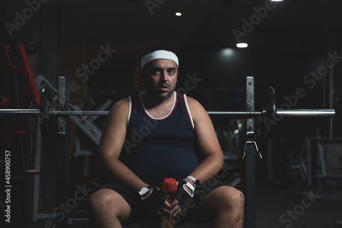a funny fat boy doing sports inside a gym.
overcoming concept.
willpower. photo