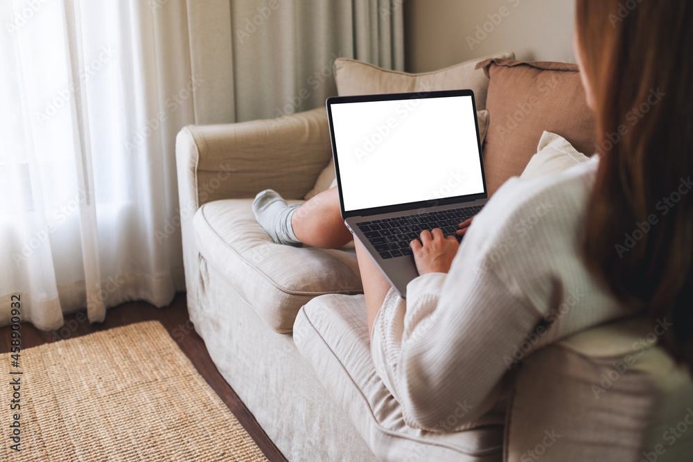 Mockup image of a woman working and typing on laptop computer with blank screen on sofa at home Mockup image of a woman working and typing on laptop computer with blank screen on sofa at home