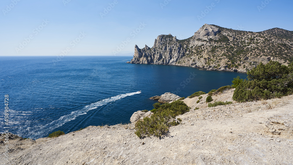 view of the sea and mountains. rocky sea coast. on the blue sea, a white trail from the boat. sunny day at the seaside. beautiful background