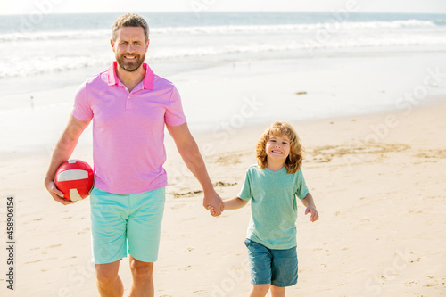 family of daddy man and child boy on beach with ball holding hands, family