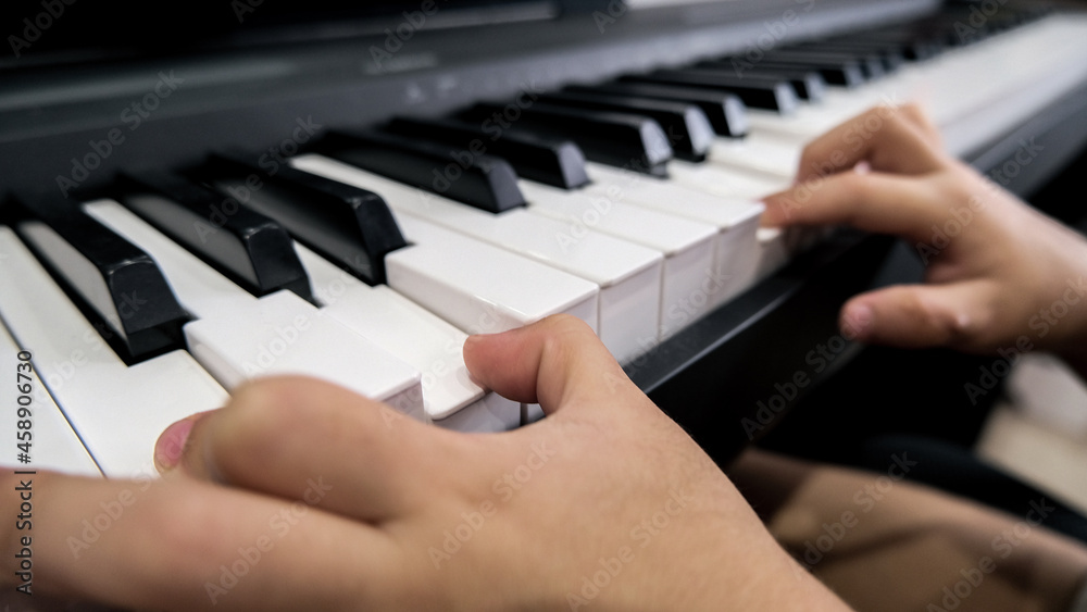 Close-up of a child's hand playing the piano . Favorite classical music. musical instruments for teaching music at home. The concept of a musical instrument. Self-education Close-up of a child's hand playing the piano . Favorite classical music. musical instruments for teaching music at home. The concept of a musical instrument. Self-education