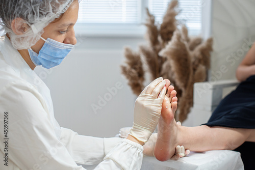 Pedicurist master makes pedicure on woman's legs. Woman giving a professional pedicure at the beauty spa salon. Woman body care. Relaxing, feet spa treatment. Closeup, selective focus