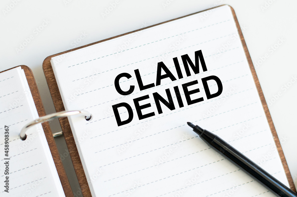 White notebook with the text CLAIM DENIED on the table with black marker. Business concept White notebook with the text CLAIM DENIED on the table with black marker. Business concept