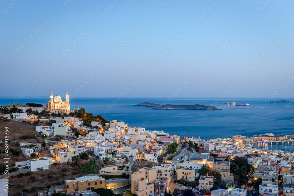 Panoramic view of Ermoupolis, the capital of Cyclades, Greece, with the Church of the Resurrection of Our Savior on the left and the Aegean Sea in the background. Photo taken from Ano Syros, blue hour
