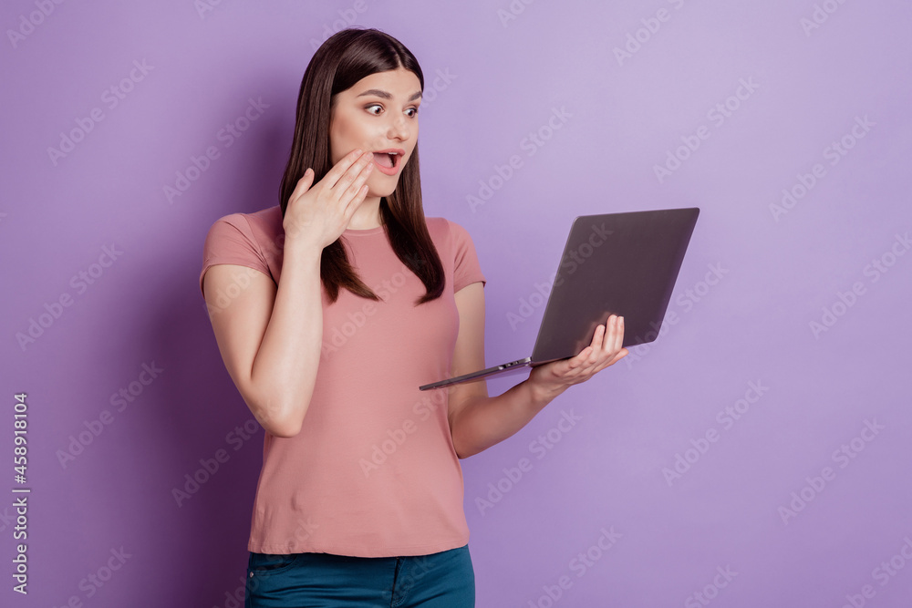 Portrait of positive successful woman happy positive smile look laptop amazed surprised news isolated over violet color background Portrait of positive successful woman happy positive smile look laptop amazed surprised news isolated over violet color background