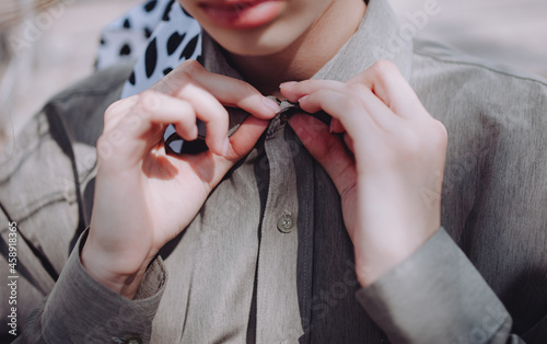 a girl buttons up her pistachio shirt