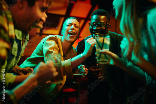 Happy African American couple signing karaoke party and having fun in a bar.