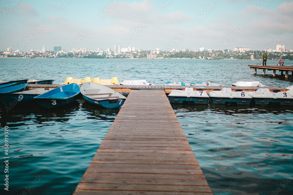 Obraz premium white and blue boats on the pier, catamarans by the water, stationary boats and catamarans at the pier